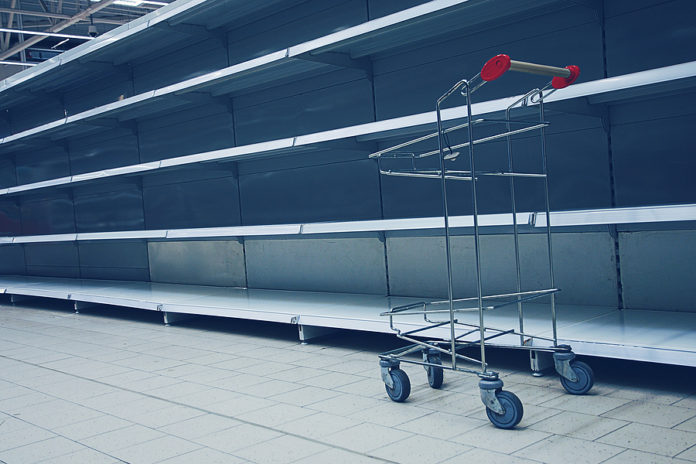 Shopping Trolley In Front Of Empty Shelves In Grocery Store