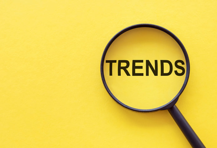 Trends Text Written On Magnifier Glasses, On Yellow Background.
