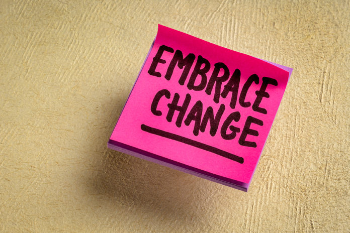 embrace change - handwriting on a reminder note against texture