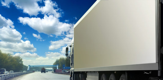 White truck on asphalt road under blue sky with clouds