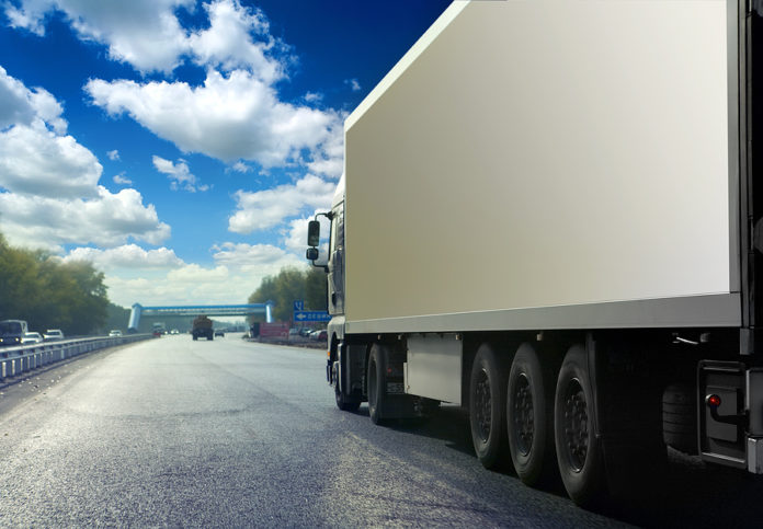 White truck on asphalt road under blue sky with clouds