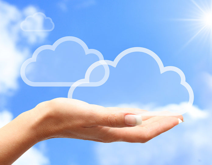 Hand with cloud computing symbol against blue sky.