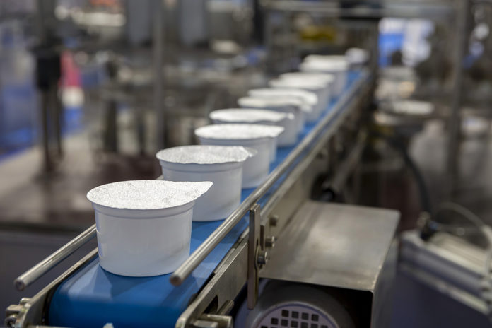 White Yogurt Packages On A Production Line In A Dairy Farm.