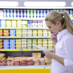 Rising Food Prices Impact Brand Loyalty, Expiration Dates, and Consumer Values woman reading her shopping list in the supermarket with copy spa
