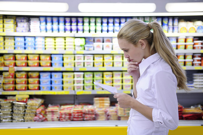 woman reading her shopping list in the supermarket with copy spa