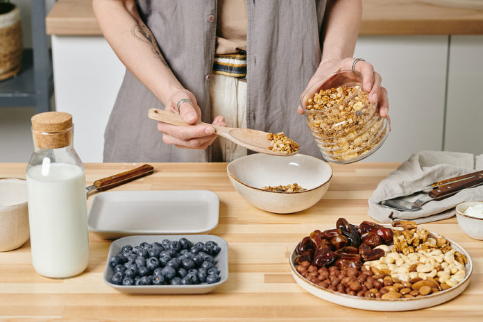 Hands of person preparing vegetarian breakfast by kitchen table