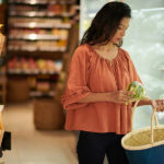 Affording Food Is the Top Consumer Concern for 2023: Attest Survey Young Woman Shopoing In Grocery Store And Buying Fresh Cauliflow
