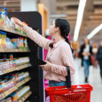Food Price Increases Decelerate in December, Inching up 0.3%: CPI Report Side View Of Young Caucasian Woman Reaches Hand To Top Shelf, Ho
