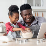 How the Digitally Native Gen Alpha Is Shaping the Future of F&B Purchasing Adorable Black Father And Daughter Baking Together, Using Digita