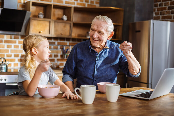 Positive Elderly Man Having Breakfast With His Granddaughter