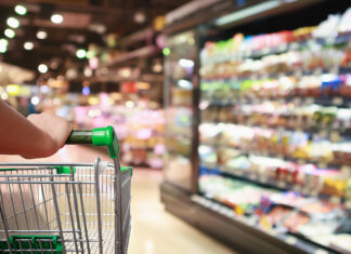 General Mills Repriced Two-Thirds of Its Portfolio and Still Lost Volume. Here’s What’s Really Growing Units. Woman Hand Hold Supermarket Shopping Cart With Abstract Grocery