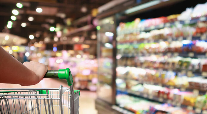 General Mills Repriced Two-Thirds of Its Portfolio and Still Lost Volume. Here’s What’s Really Growing Units. Woman Hand Hold Supermarket Shopping Cart With Abstract Grocery