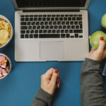 Snack-Sized Digital Content to Capitalize on the All-Day Snacking Trend Work Space With Laptop, Candy, Chips, Water And Apple And Woman
