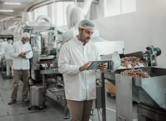 Replacing the Clipboard: Digitizing Compliance on the Factory Floor 1176094666_supervisor-evaluating-quality-food-food-plant-while-holding-tablet-Dayinlife-FoodBev_Getty