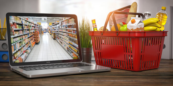 Shopping basket with food and laptop with shelf of supermarket