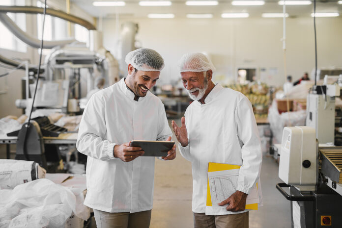 Two Cheerful Male Colleagues In Sterile Clothes Standing In Food