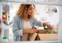 Omnichannel Consumers Lean Toward Online Grocery Shopping, Especially for Shelf-Stable Products View Looking Out From Inside Of Refrigerator As Woman Unpacks On